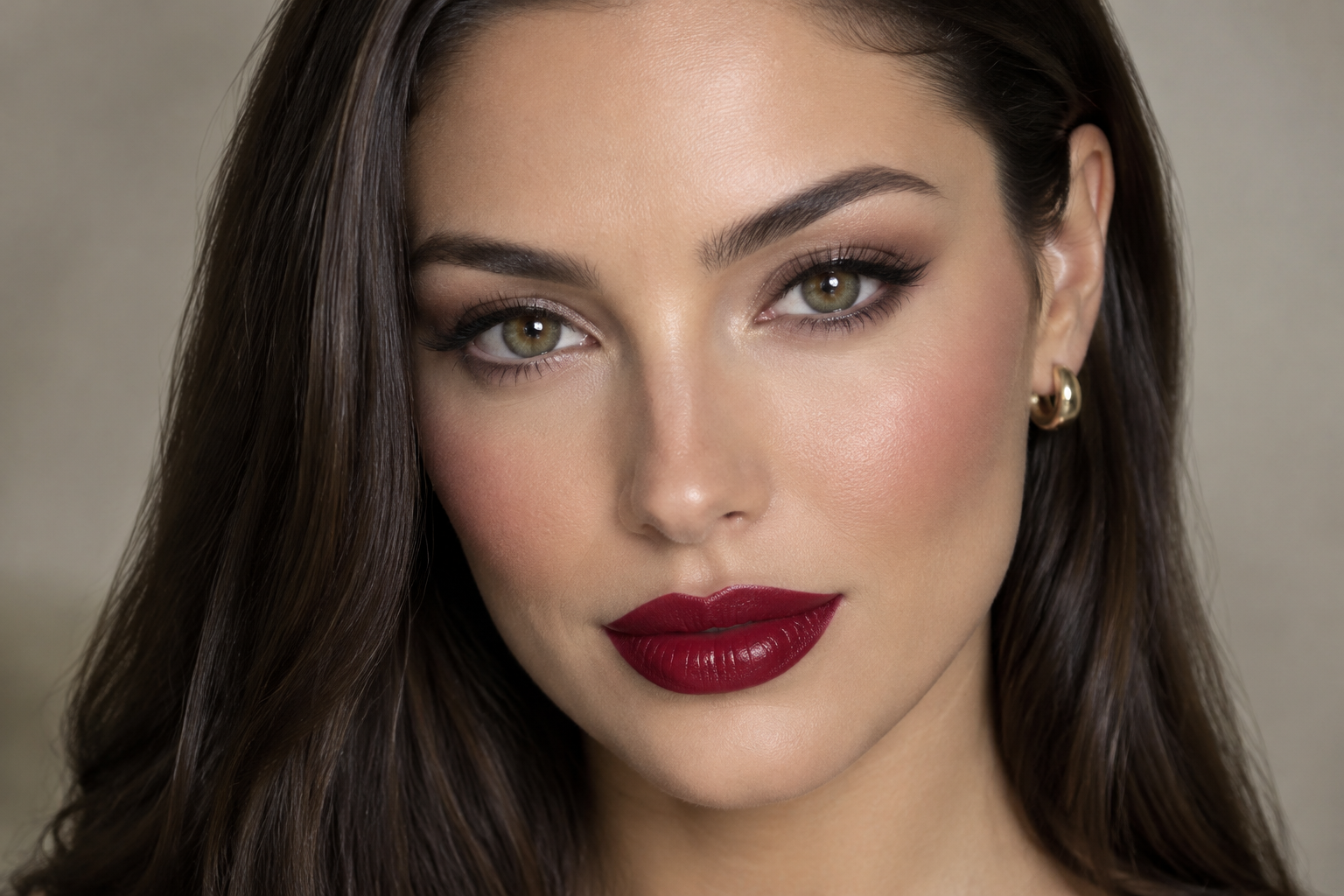 Close portrait of a woman with cherry-red lipstick, softly defined eyes, and sleek hair tucked behind one ear.